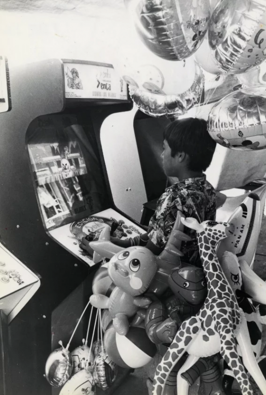 Un pequeño vendedor de globos juega frente a una máquina de videojuegos en abril de 1994. Foto: Alfonso Manzano, Archivo de EL UNIVERSAL. <br />El juego es TumblePop de Data East lanzado en 1991.